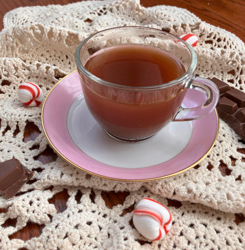 Teacup with pink saucer on a textured surface with peppermint candies.