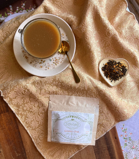 Tea cup with a spoon, tea leaves, and a tea bag on a textured cloth.