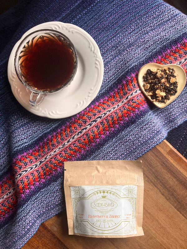 Tea cup with tea leaves, a tea bag, and a patterned cloth on a wooden surface