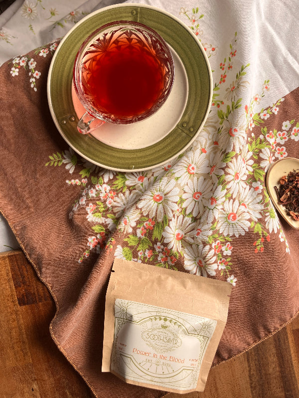 Tea cup with a floral tablecloth and tea bag on a wooden surface